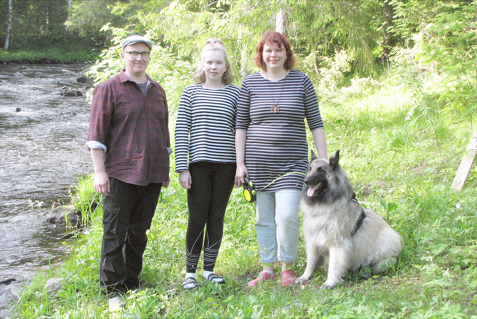Tuopanjoki kutsuu.  Tuomas, Linnea ja Hanna Hakola sekä Kossi-koira nauttivat luonnon rauhasta joen varrella olevalla mökissään.