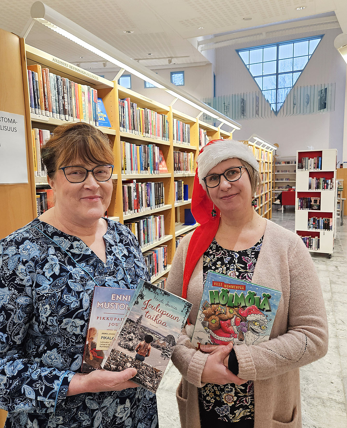 Iina Aaltonen ja Maarit Sorjonen Juuan kirjastosta esittelevät suosittuja joulunajan kirjoja.