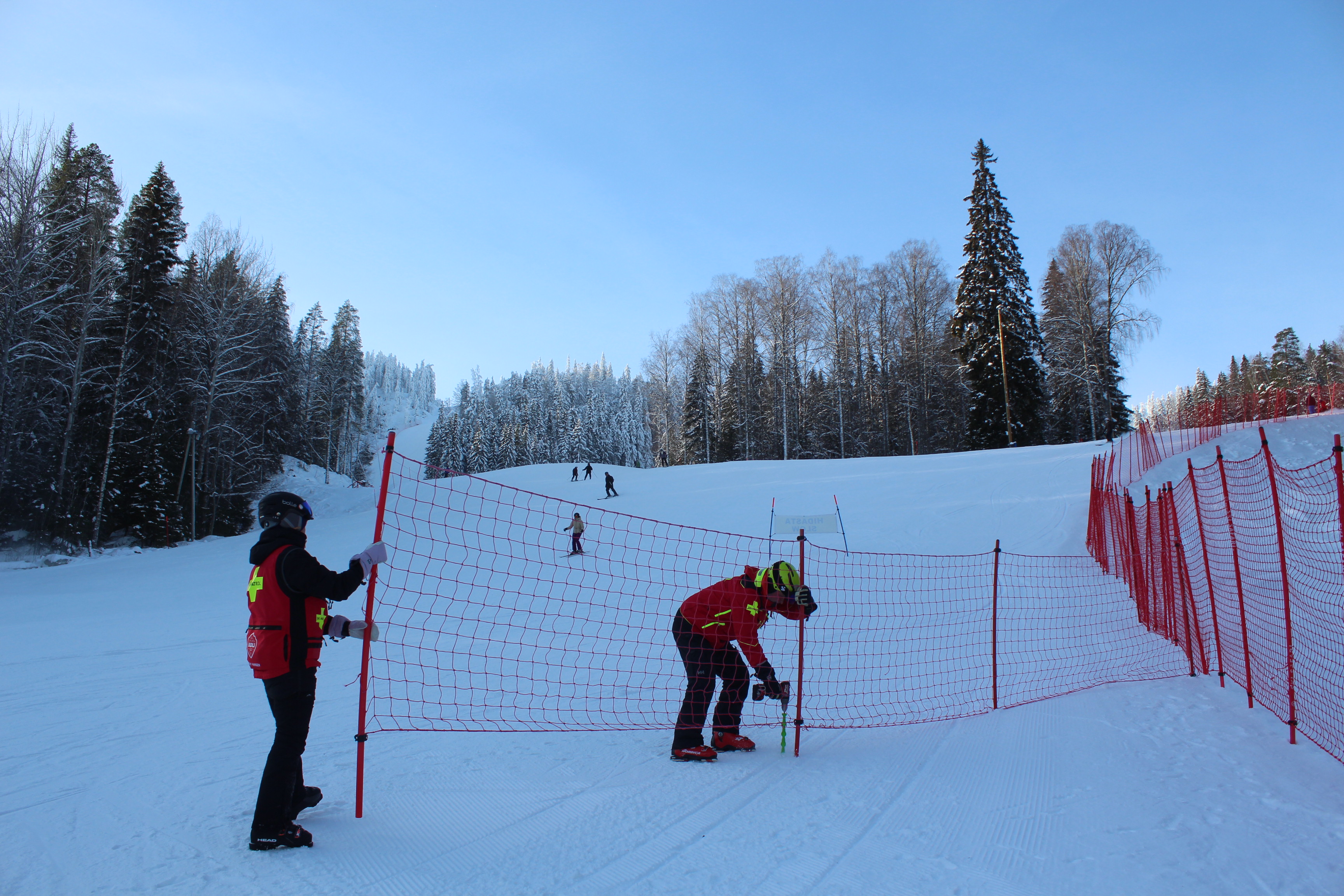 Ski patrol ja ensihoidon kenttäjohtaja Irma Lahdenperä ja Arto Mulari korjaavat laskettelurinteen turvaverkkoa.