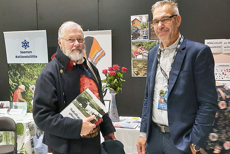 Kai Iiskola (oik.) lahjoitti Juuka-seuran historiateoksen Kotiseutuliiton puheenjohtaja Janne Vilkunalle. Kuva Eija Meriläinen