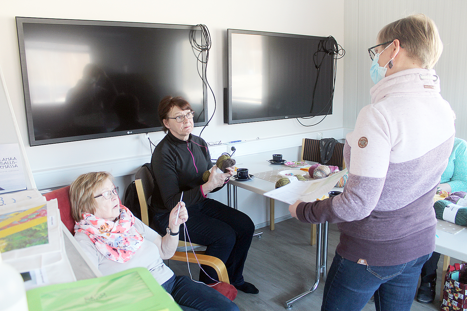 Sirkka Simonen (vas.) ja Seija Vatanen aloittelemassa neulettaan Maarit Sorjosen (selin) neuvojen mukaisesti.