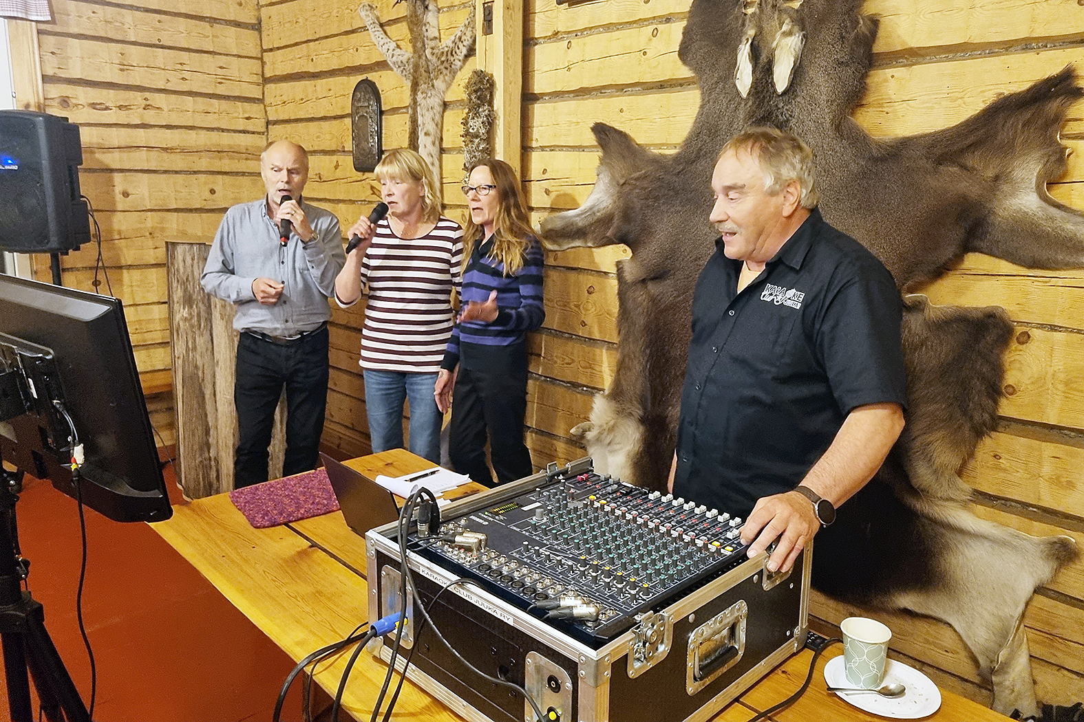 Karaokeisäntä Esko Nevalainen taustoittaa Olavi Penttisen (vas.), Seija Penttisen ja Sirpa Miettisen yhteisesitystä.