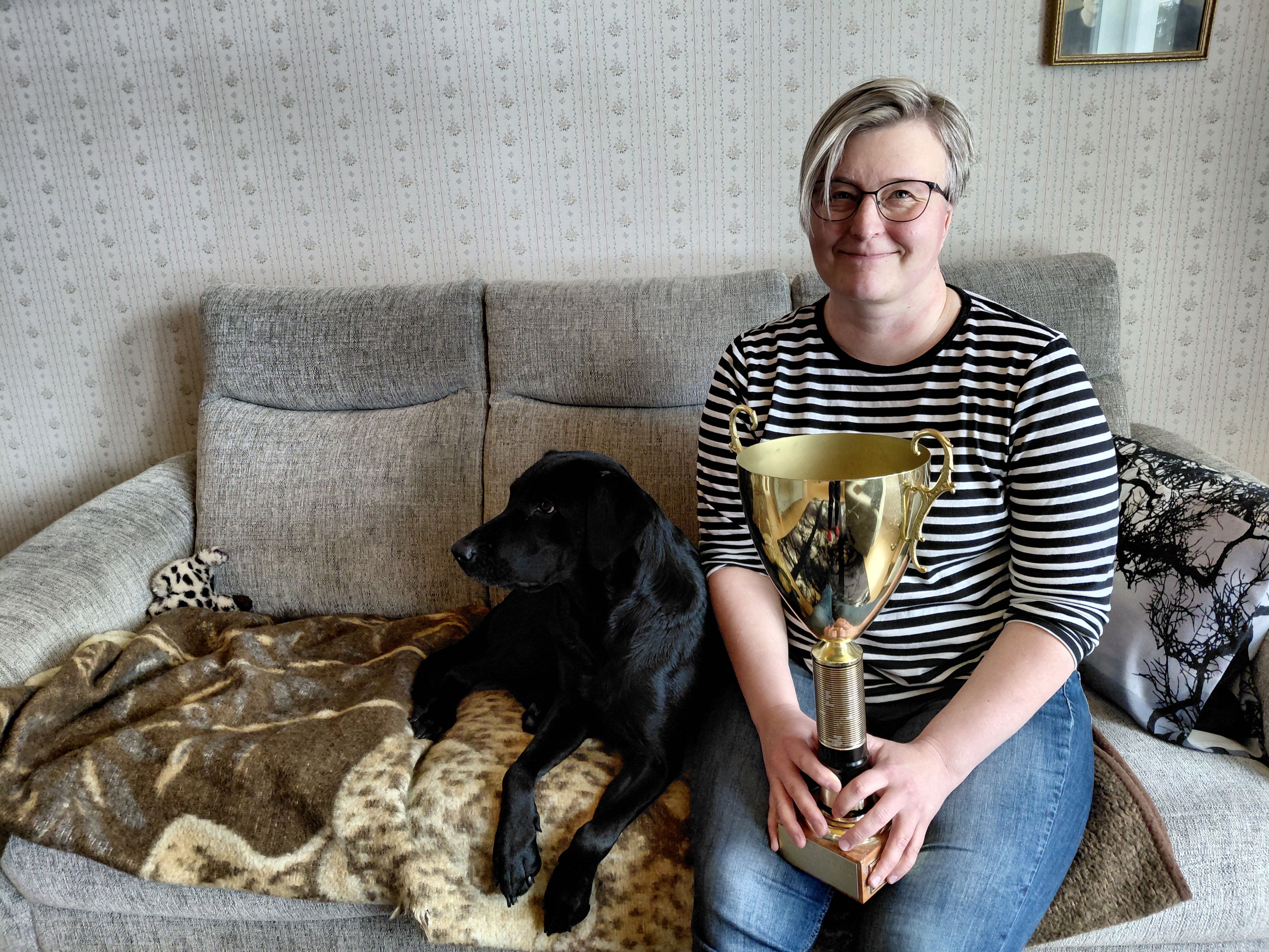 Vuoden Erämiehen palkinto oli iso yllätys. Niina Kettusen kanssa sohvalla makoilee labradorinnoutaja Miina.