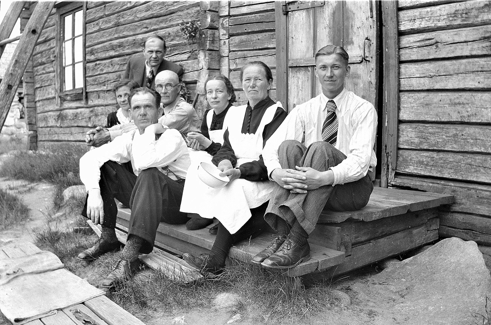 Tuomelan portailla takarivissä vas. Eino Kettunen, Tauno Kettunen, Elsa Keurulainen (o.s. Kettunen, Taunon ja Annan tytär), Anna Kettunen (o.s. Huttunen Taunon vaimo), todennäköisesti Otto Kettunen (Taunon ja Einon veli), eturivissä vas. Elsa Kettunen (os. Kukkonen, Viljo Kettusen vaimo), Hannes Keurulainen (Taunon ja Annan vävy).  