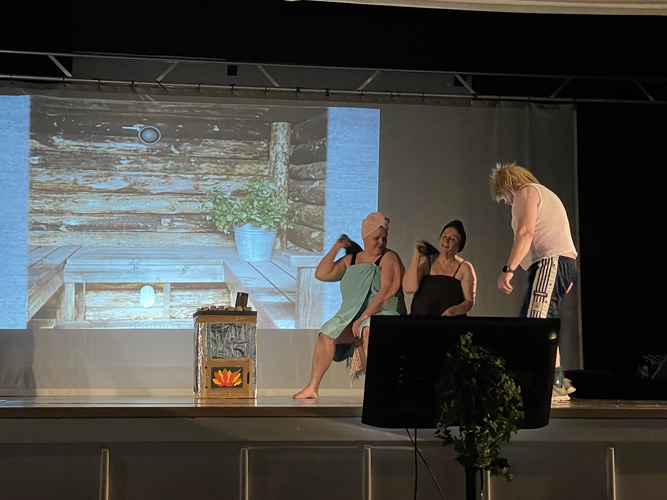 Kalle Korpinen (Esko Nevalainen) saunottamassa naisia (Jetta Pääskyvuori ja Silja Möttönen).