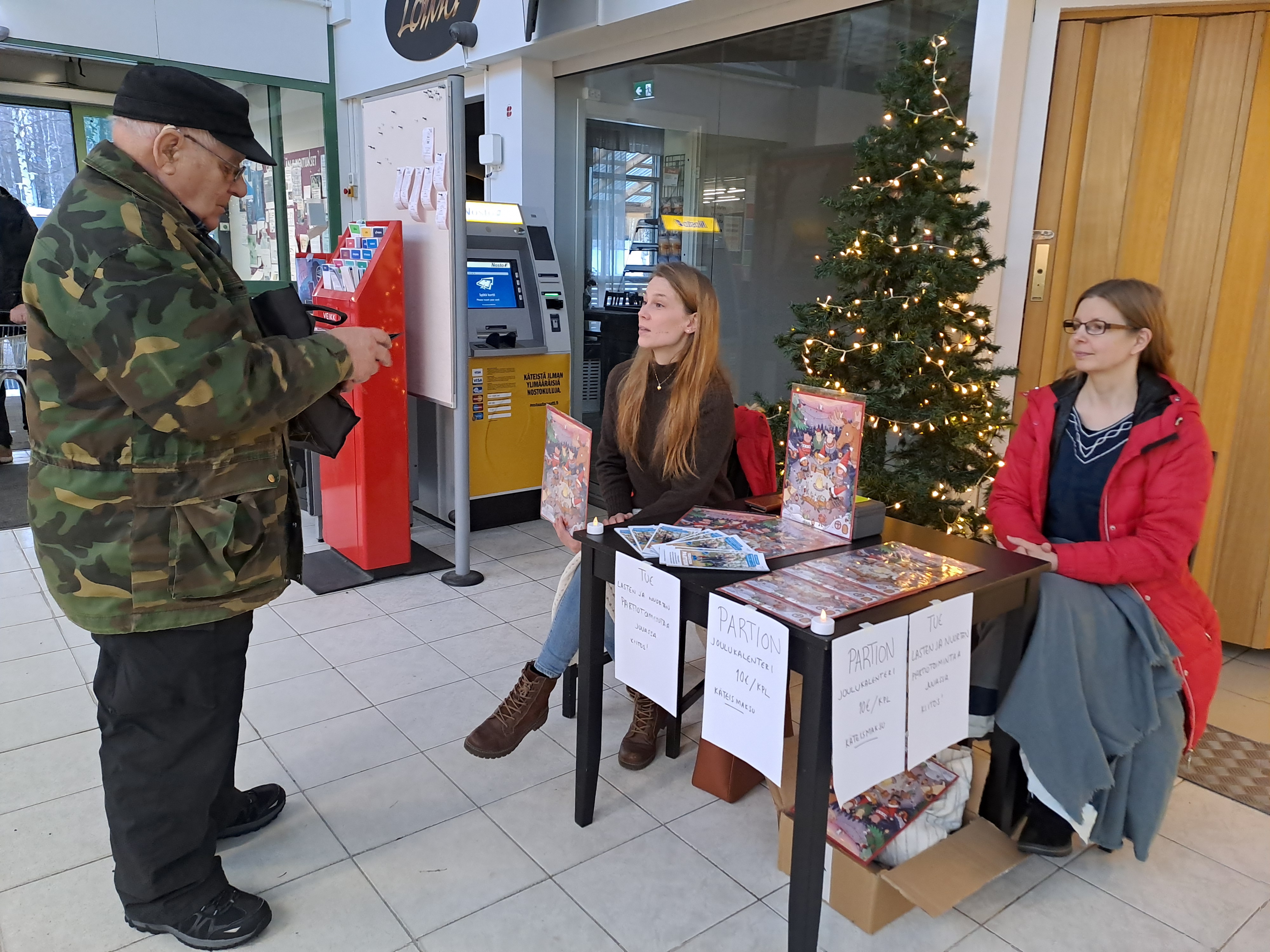 Jouni Kallinen halusi tukea partiolaisten toimintaa. Kalenteria myymässä Laura Huttunen ja Ilona Haukka Juuan Kiitäjistä. 