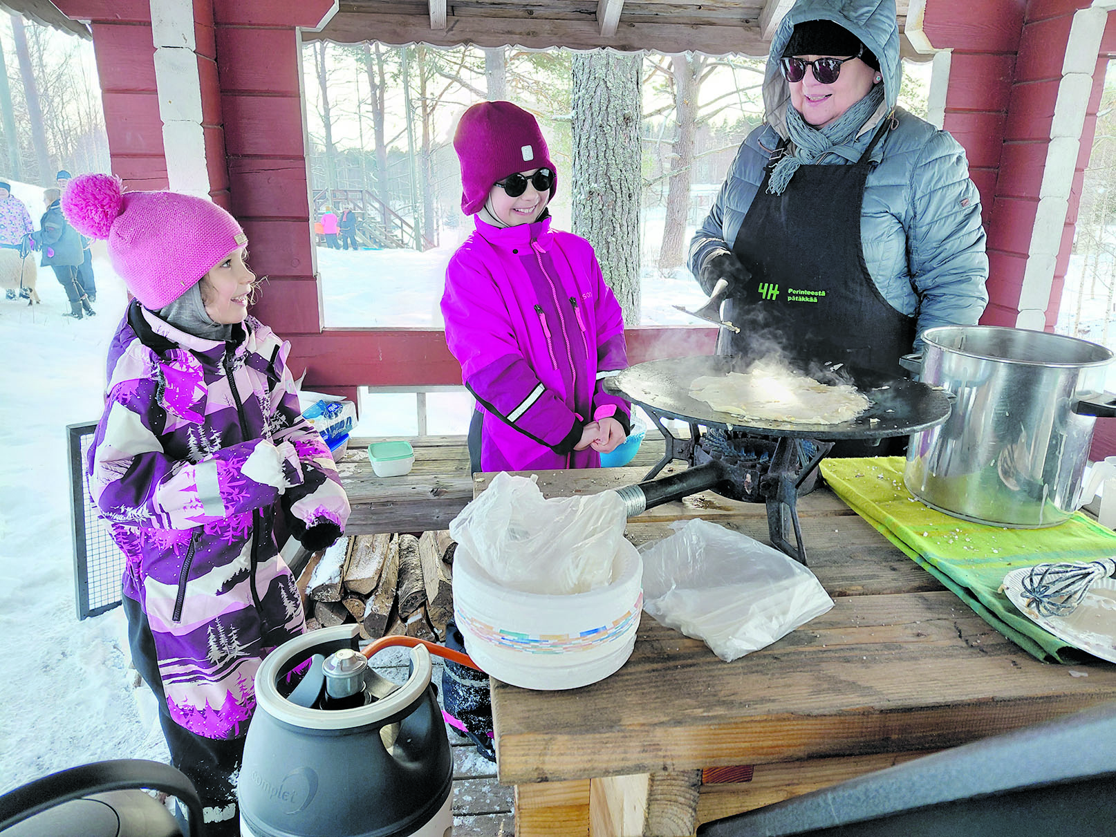 
–Mun lettu on kohta valmis, iloitsee kahdeksanvuotias Elli Toropainen Kuopiosta Jaana Tiaiselle (oik.). Tiainen on Perinteestä pätäkkää- hankekoordinaattori. Kuusivuotias pikkusisko Malla Toropainen odottaa letunpaistovuoroaan.









