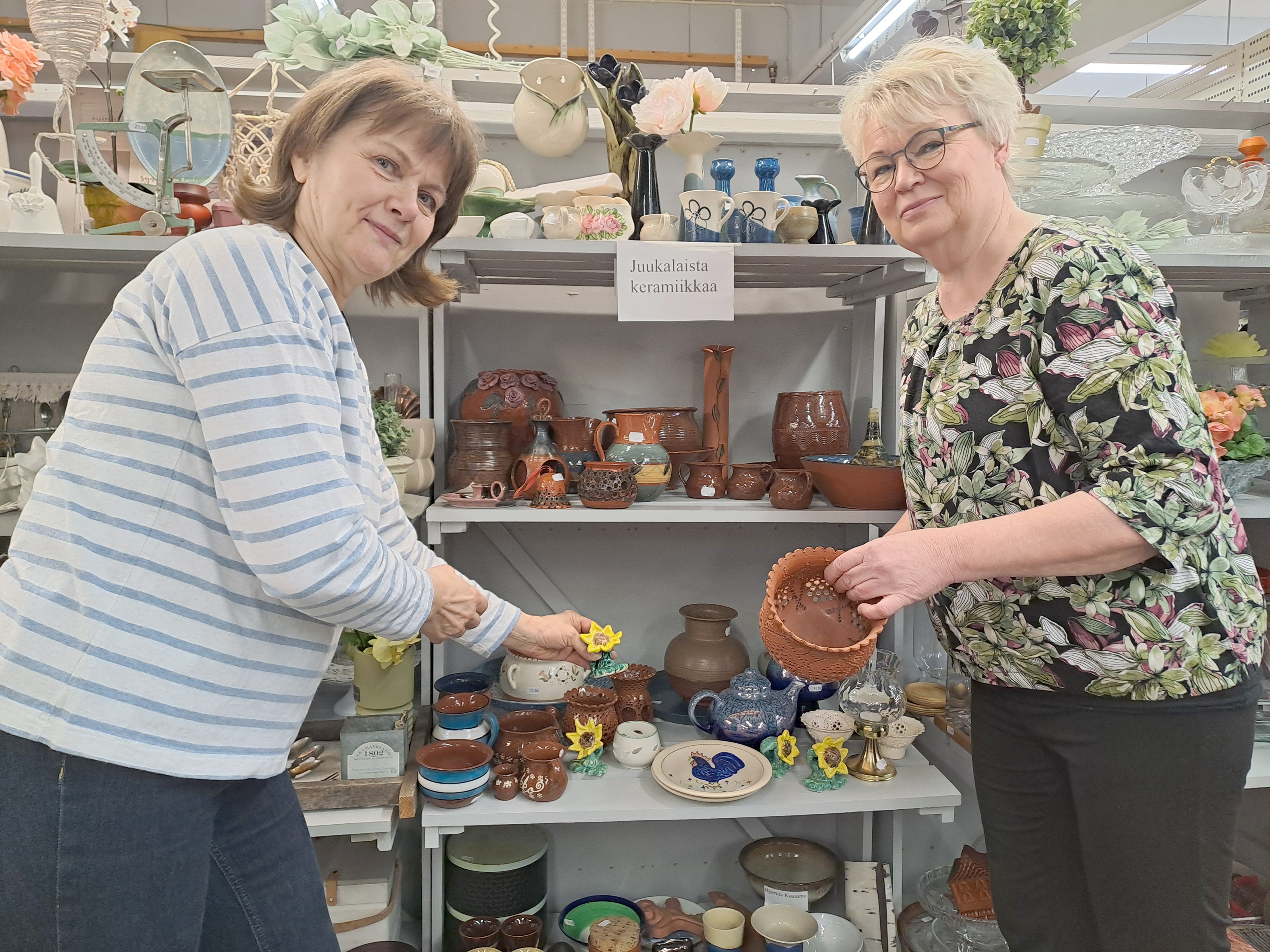 Taru Nevalainen (vas.) ja Sari Kortelainen esittelevät juukalaisen keramiikan hyllyä. Lahjoja voisi löytyä täältäkin?


